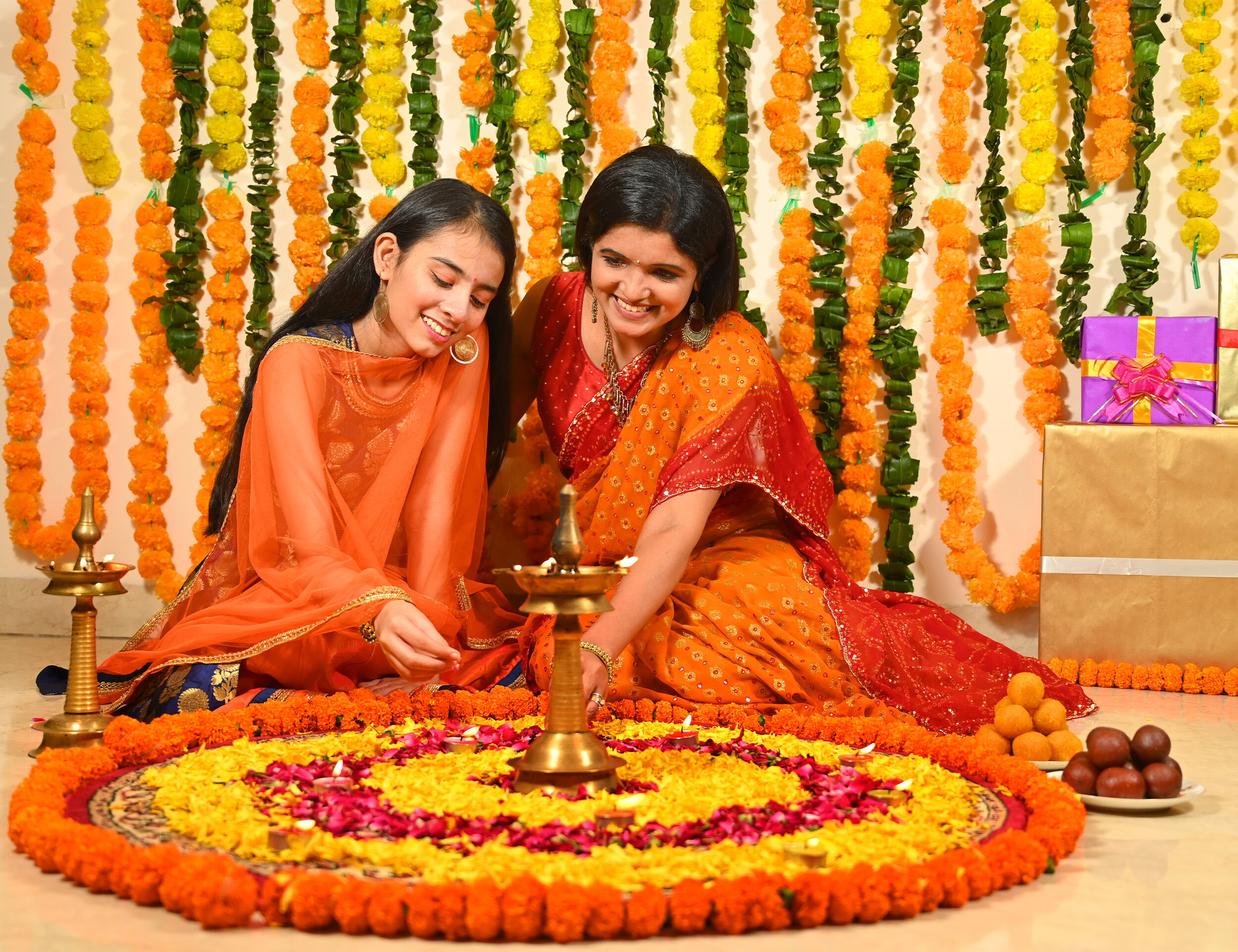 Mother and daughter creating a beautiful mehendi decoration at home with fresh flowers.